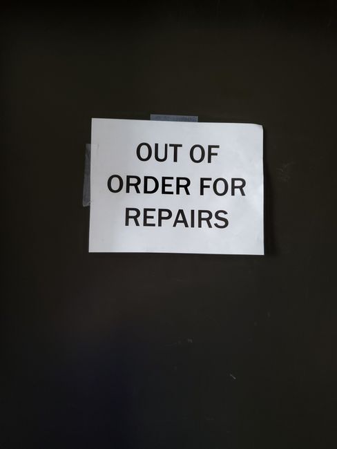 A white paper printed with the message 'OUT OF ORDER FOR REPAIRS' is taped to a dark, smooth surface, likely a wall or door, in an indoor setting. The sign indicates that the area or equipment is temporarily unavailable due to maintenance work. The lighting in the environment appears even, highlighting the sign clearly. This image does not include any cleaning tools or surfaces but focuses on the informational notice, which may relate indirectly to maintenance and cleanliness of the space. Putney Carpet Cleaners, as a professional cleaning service, emphasizes surface cleaning and maintenance to ensure hygiene and proper upkeep of residential or commercial premises, consistent with the context of building repairs and maintenance.